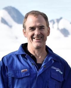 Portrett av en smilende mann i blå kjeldress