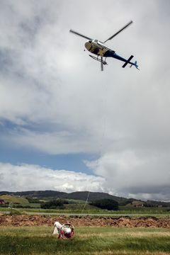 Et høydebilde av et flygende helikopter og en målesonde på bakken.
