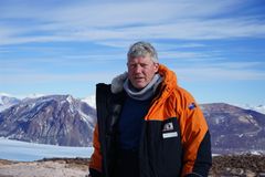 Person i vinterklær foran et snødekt fjellandskap.