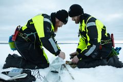 To forskere i vernedrakter arbeider med utstyr på isen i Antarktis.