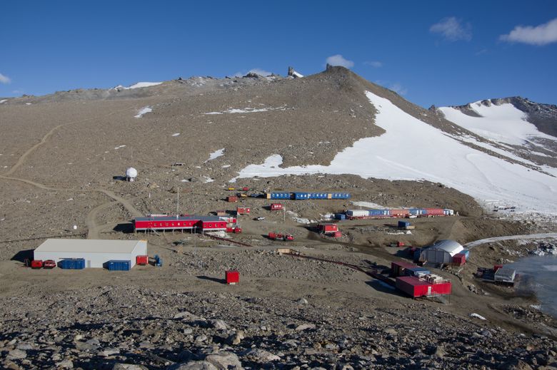 Flere bygninger plassert på stein med fjell i bakgrunnen.