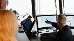 En nautiker peker på en dataskjerm og forklarer maritime sektorer for andre personer.
