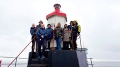 En gruppe mennesker står samlet foran en fyrlykt.