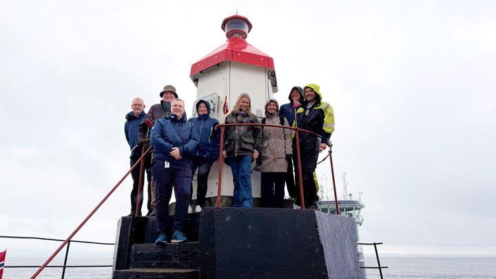 En gruppe mennesker står samlet foran en fyrlykt.