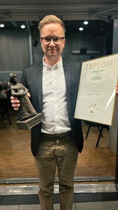 Mann med diplom og statuett.