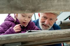 Barn opptatt med nettbrett og eldre mann som ser inn i kameraet