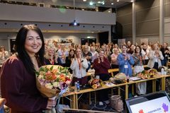Tove Holst Skyer med blomsterbukett i hendene står foran en applauderende forsamling