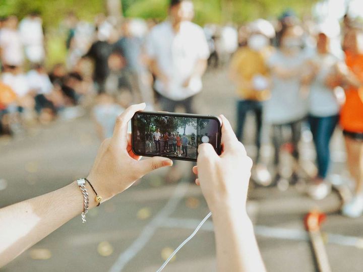 Tar et bilde med en smarttelefon av en gruppe mennesker som står i bakgrunnen.
