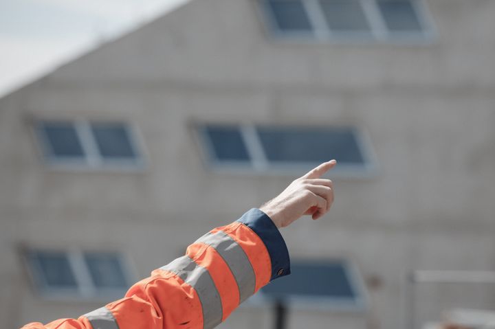 En bygningsarbeider peker oppover.