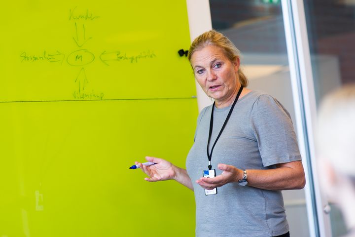 Bilde av konsernsjef i SINTEF, Alexandra Bech Gjørv, som snakker i et møterom foran en tavle hun har skrevet på.