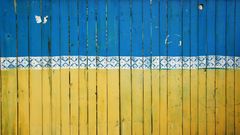 Malt plankegjerde i blått øverst og gult nederst med en bord i mellom, som et Ukrainsk flagg