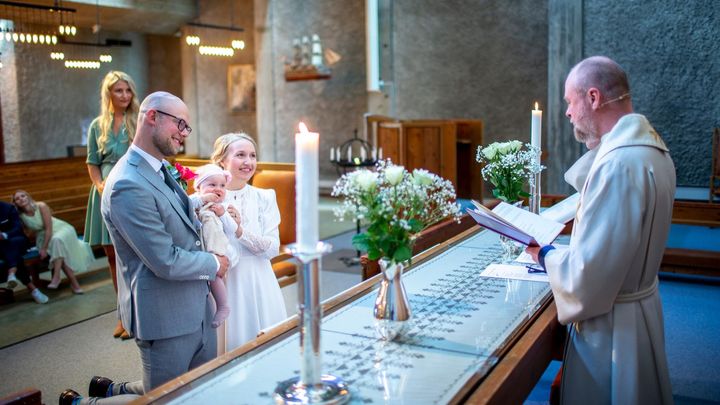 Et brudepar ved alteret i en kirke med prest.