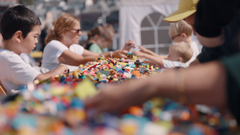 barn og voksne som sitter ved et bord fullt av lego