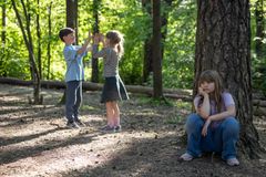 Barn leker i skogen - ei jente sitter alene