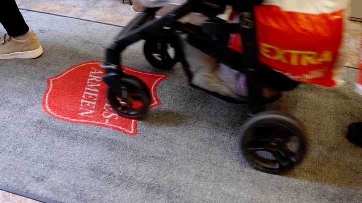 Barnevogn på teppe med Frelsesarmeens logo - og handlepose hengende på siden.