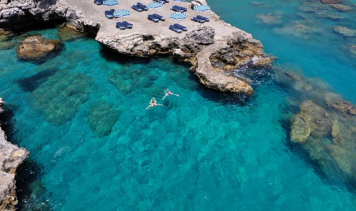 Turister som svømmer i asurblått hav på Rhodos