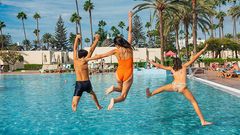 Tre barn som hopper ut i et basseng på Gran Canaria