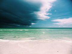 Vakker strand med mørke uværskyer på himmelen.