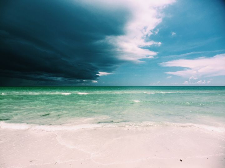 Vakker strand med mørke uværskyer på himmelen.
