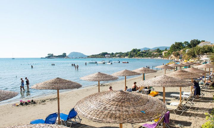 Strand i Hellas med mange mennesker som soler og bader.