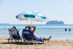 Et par som ligger på hver sin solseng på en strand i Zakynthos Hellas.