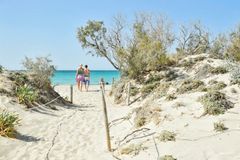 Et par som vandrer på stranden Elafonissi på Kreta.