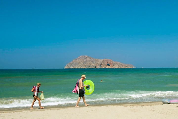En far og en datter som leker i vannet på en strand i Platanias på Kreta.