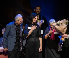 Musikkterapeut og korleder Jelena Golubovic ( i midten) får blomster og takk under Demenskorets konsert på Chat Noir i første sesong. Hun blir også med i andre sesong. FOTO: JULIA MARIE NAGLESTAD/NORDISK BANIJAY / NRK