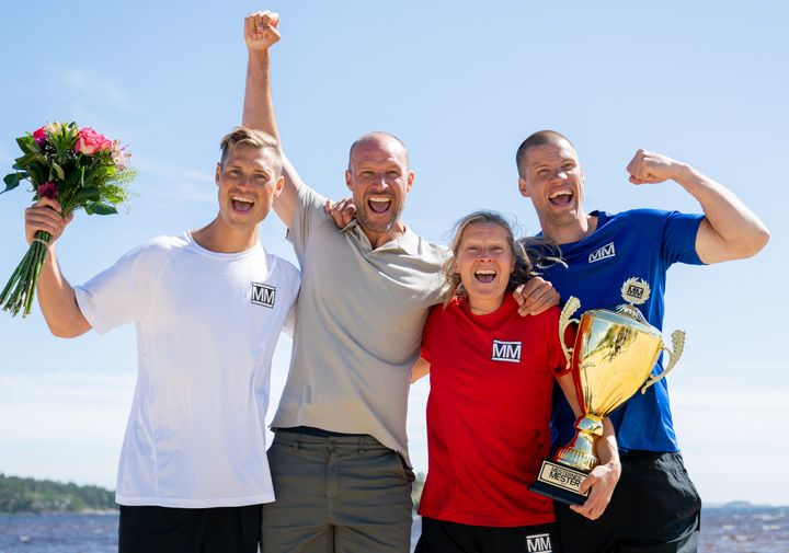 Fire%20jublende%20mennesker%20som%20holder%20rundt%20hverandre%20p%E5%20rekke%20-%20en%20kvinne%20med%20pokal%20og%20tre%20menn.