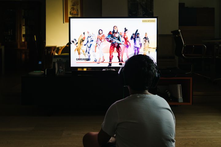 En tenåringsgutt avbildet bakfra. Han sitter på gulvet foran en tv og spiller Fortnite.