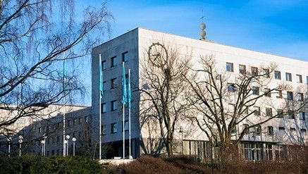 Radiohuset på Marienlyst med en stor klokke på veggen. Foran hovedinngangen er det NRK-flagg på tre flaggstenger.