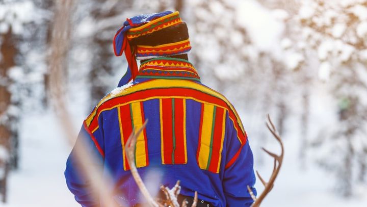 Samisk mann fotografert bakfra i vinterlandskap.