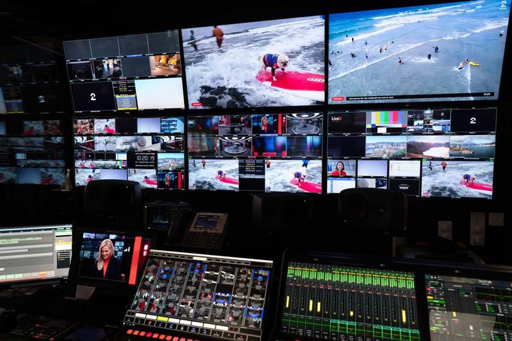 Regi-panel og tv-skjermer. Knapper og spaker i forgrunnen og store skjermer med mange forskjellige bilder på veggen bak.