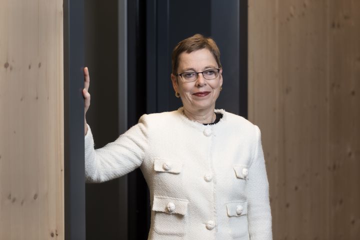 Portrettbilde av Mari Velsand. Hun står ved en vegg, og den høyre armen er løftet mot veggen mens hun ser i kamera. Hun har på seg hvit jakke.