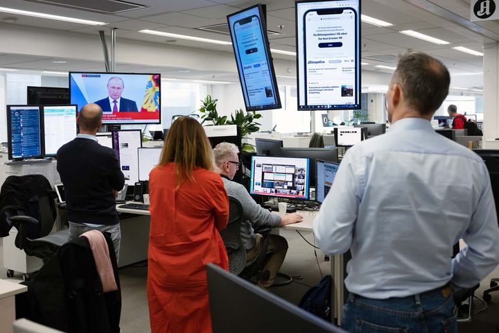 Frå redaksjonen i Aftenposten. Tre personar står og følgjer med på ein av skjermane der det er bilete av Russlands president Vladimir Putin.
