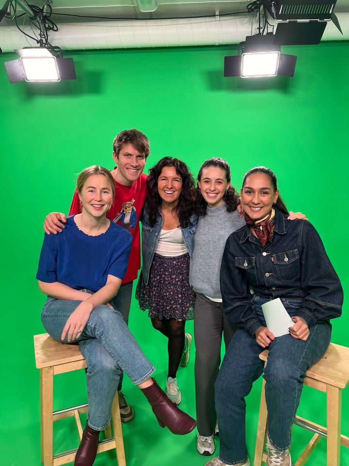 En gruppe på fem personer sitter på krakker foran en grønn skjerm i et studio.