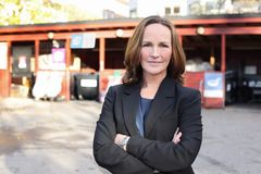 Stine Helgeland i en mørk dress står med armene krysset foran en gjenvinningsstasjon.