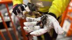 Person med hansker viser frem brente rester av batterier og annet avfall.