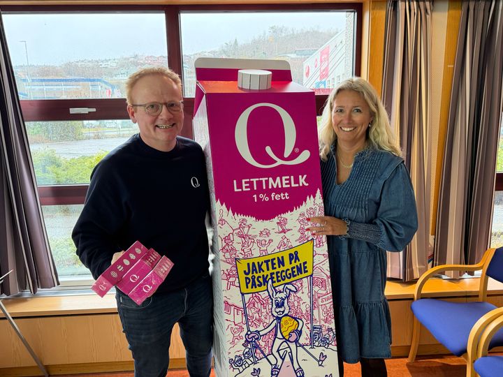 Representanter fra Q-Meieriene står rundt en stor Q-melkekartong med påskedesign. De smiler.