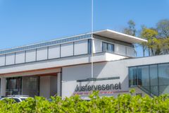 Hvitt bygg med teksten Justervesenet på, grønn hekk