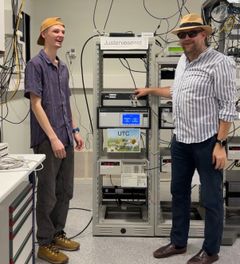 Overingeniør Nikolai Drivdal (t.v.) og Noreg sin tidssjef Harald Hauglin fyrer opp sommarstemninga framfor racket med atomklokkene som er med på å bestemme verdas tid.