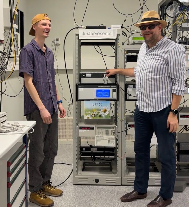 Overingeniør Nikolai Drivdal (t.v.) og Noreg sin tidssjef Harald Hauglin fyrer opp sommarstemninga framfor racket med atomklokkene som er med på å bestemme verdas tid.