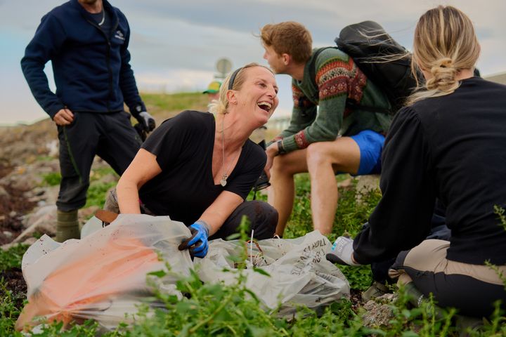 Frivillige plukker søppel på strandet.