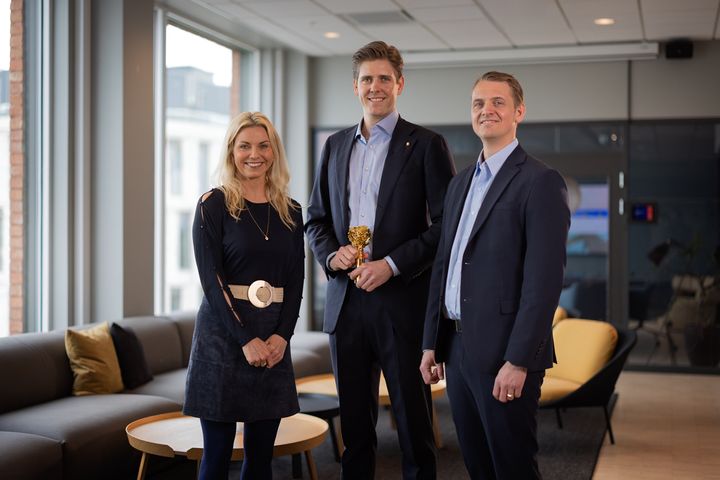 - Vi er veldig stolte og ydmyke for samfunnsansvaret til KONGSBERG innen teknologi, sikkerhet og beredskap, sier HR-direktør Ørjan Stengelsrud (til høyre) og Oscar Helvig, HR & Employer Branding Specialist. Her får de trofeet som viser at selskapet er Norges mest attraktive arbeidsgiver 2026 av administrerende direktør i Randstad, Marianne Hagen (til venstre)