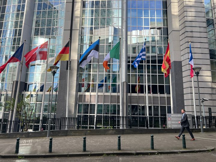 Mann går forbi mange flagg utenfor EU-bygninger i Brussel.