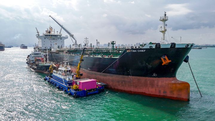 ECOsubseas vaskerobot ligger på siden av et stort tankskip i Singapore havn og vasker skroget.