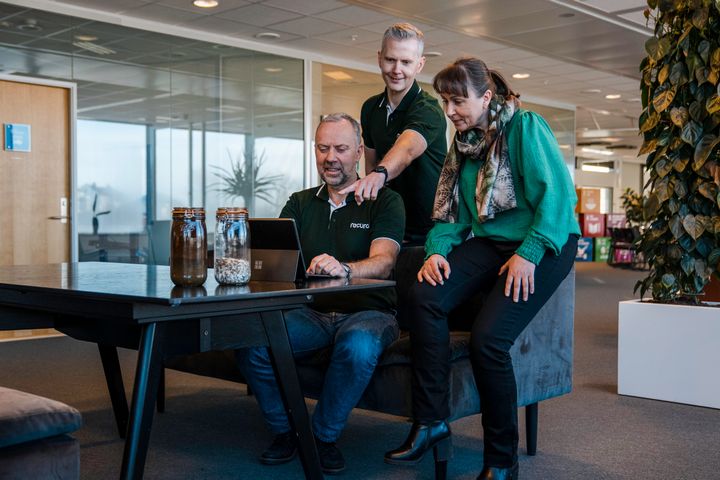 Administrerende direktør Arve Jakobsen (f.v.), teknisk sjef Bjørnar Tunheim og HMS-sjef Vibeke Aarseth i Recuro AS ser på en datamaskin i et kontorlandskap.