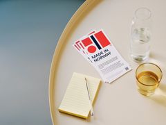 Notatblokk, blyant, glass med vann og brosjyre med "Made in Norway"-logo på rundt bord.