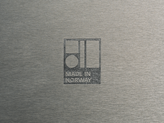 Grafisk emblem med teksten "Made in Norway" på en metallisk overflate.
