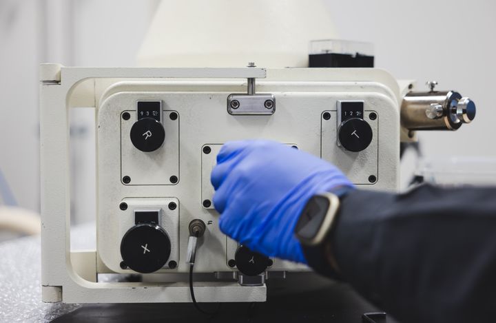 En person med blå hanske justerer en maskin hos Bergen Carbon Solutions.